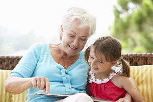 Image of Grandma with hearing aids reading to granddaughter.