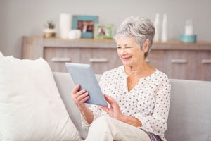 Image of woman using tablet to watch hearing aid virtual conversation.