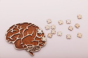 Alzheimer's disease and memory loss concept. Brain and wooden puzzle on a pink background.