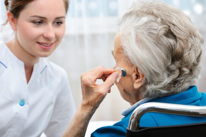 Elderly woman discussing over-the-counter hearing aids with a female audiologist