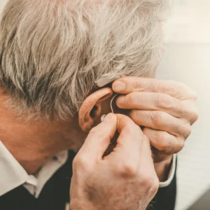 Elderly man fitting hearing aid